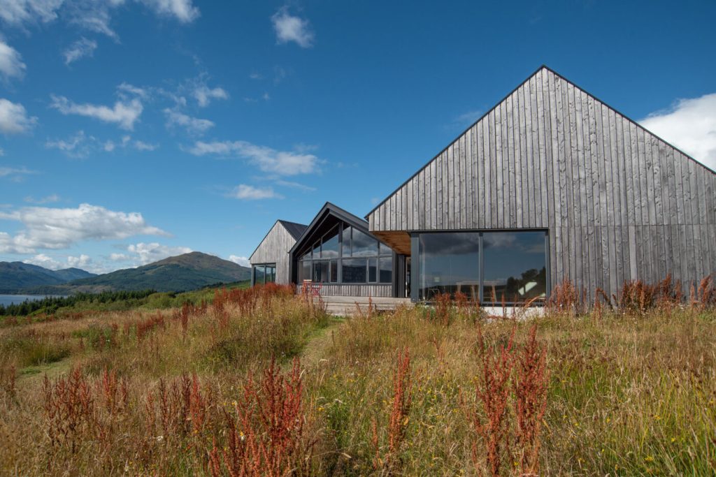 A Scottish field overlooking a loch and low hills with an artist's barn in foreground